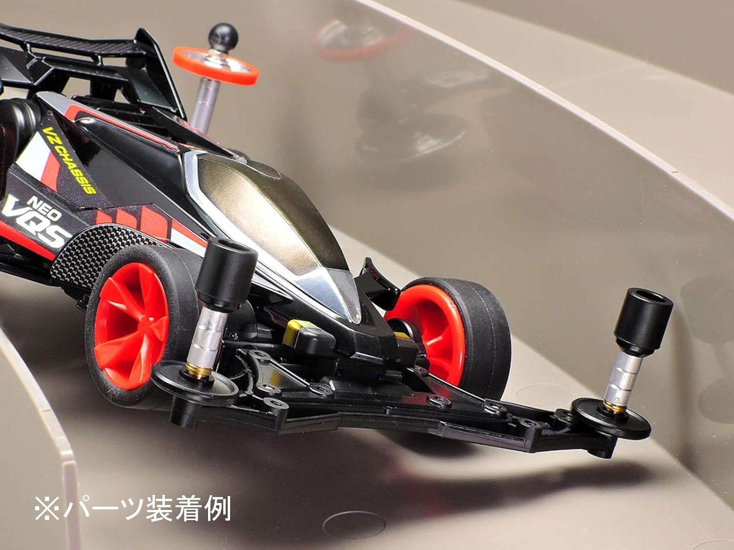 Tamiya Mini 4WD car with the JR Hi-Mount Tube Stabilizer installed, shown on a track section. The stabilizer tubes are positioned to contact the track walls.