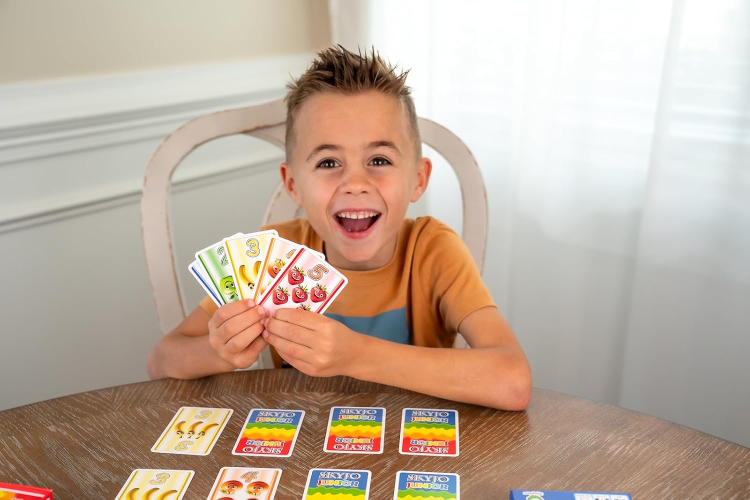 Boy happily holding a hand of SKYJO Junior cards