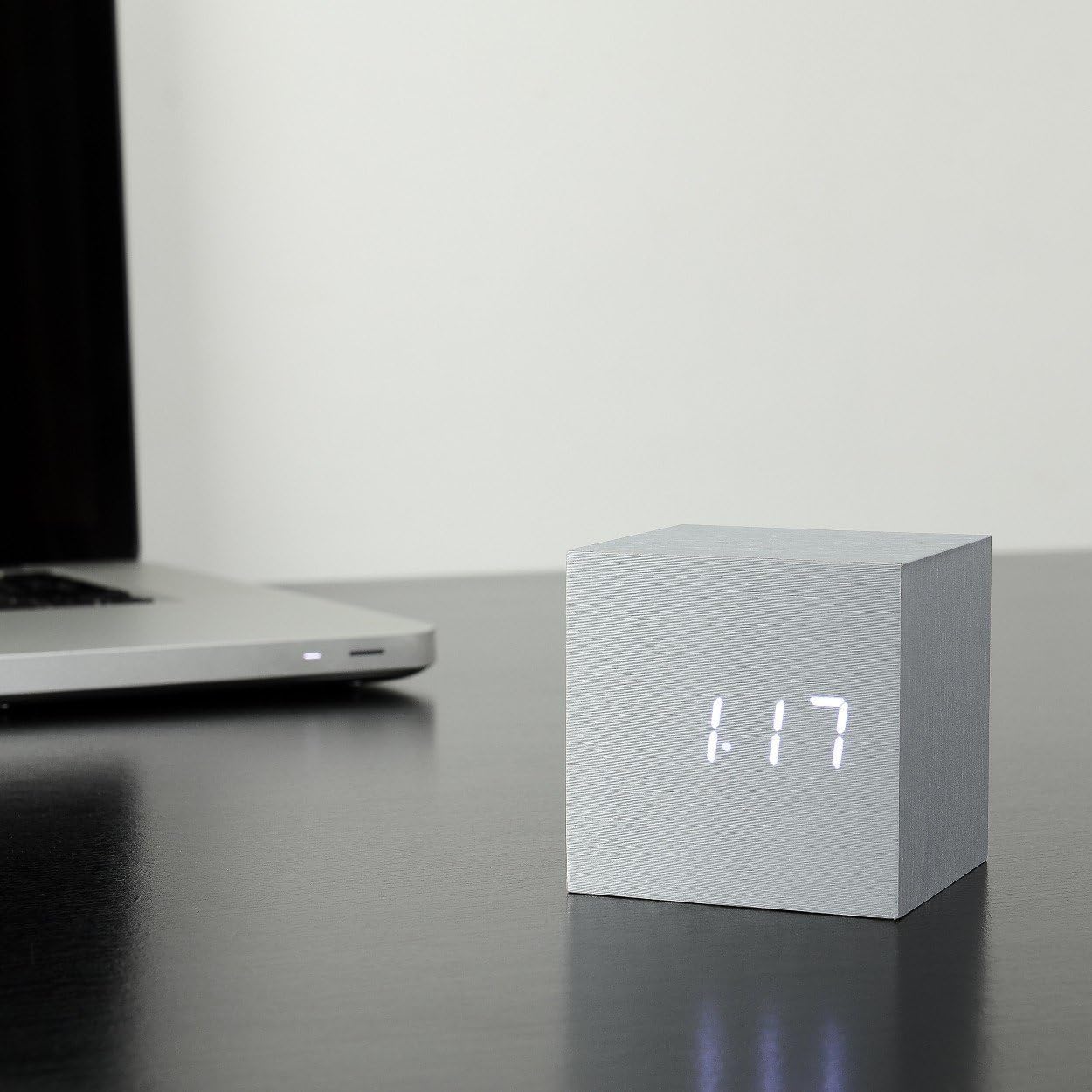 Gingko Design Cube Alarm Clock on a desk, displaying the date 1:17.