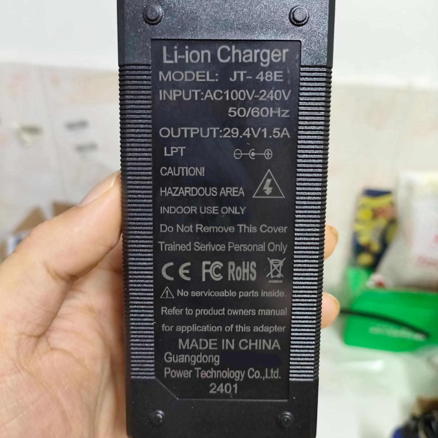Close-up of the charger's label showing model number, input/output specifications, and safety warnings like 'HAZARDOUS AREA' and 'INDOOR USE ONLY'