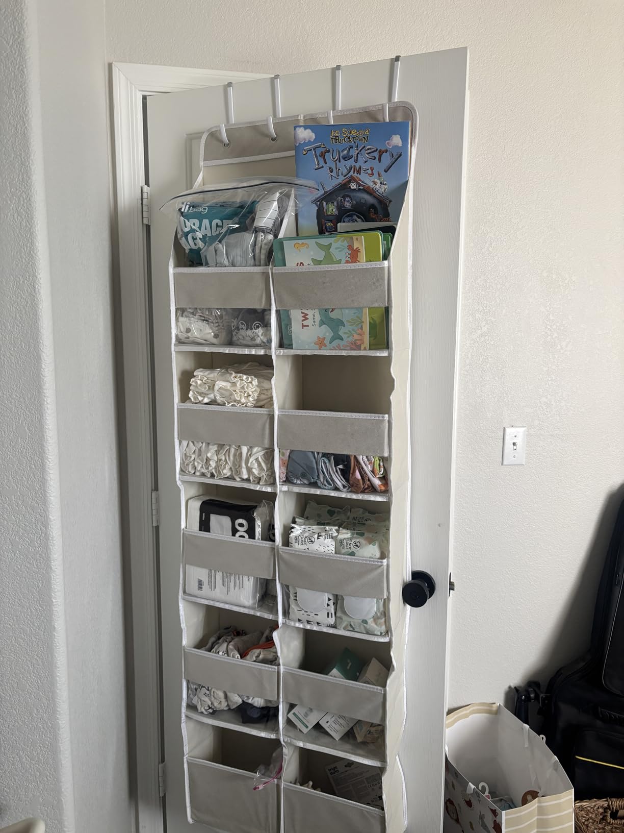 Over-the-door storage organizer with multiple pockets holding baby items