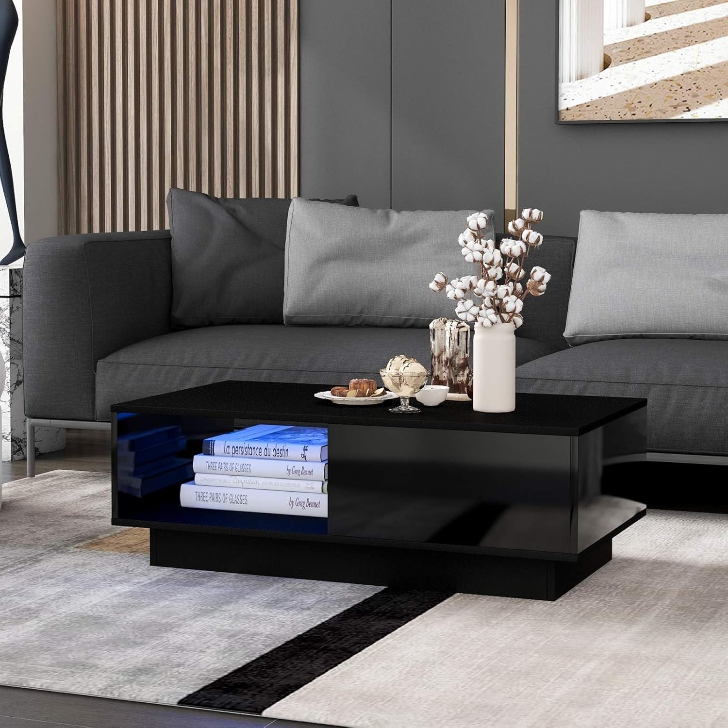 A black modern coffee table with LED lighting and storage, placed in a contemporary living room setting.