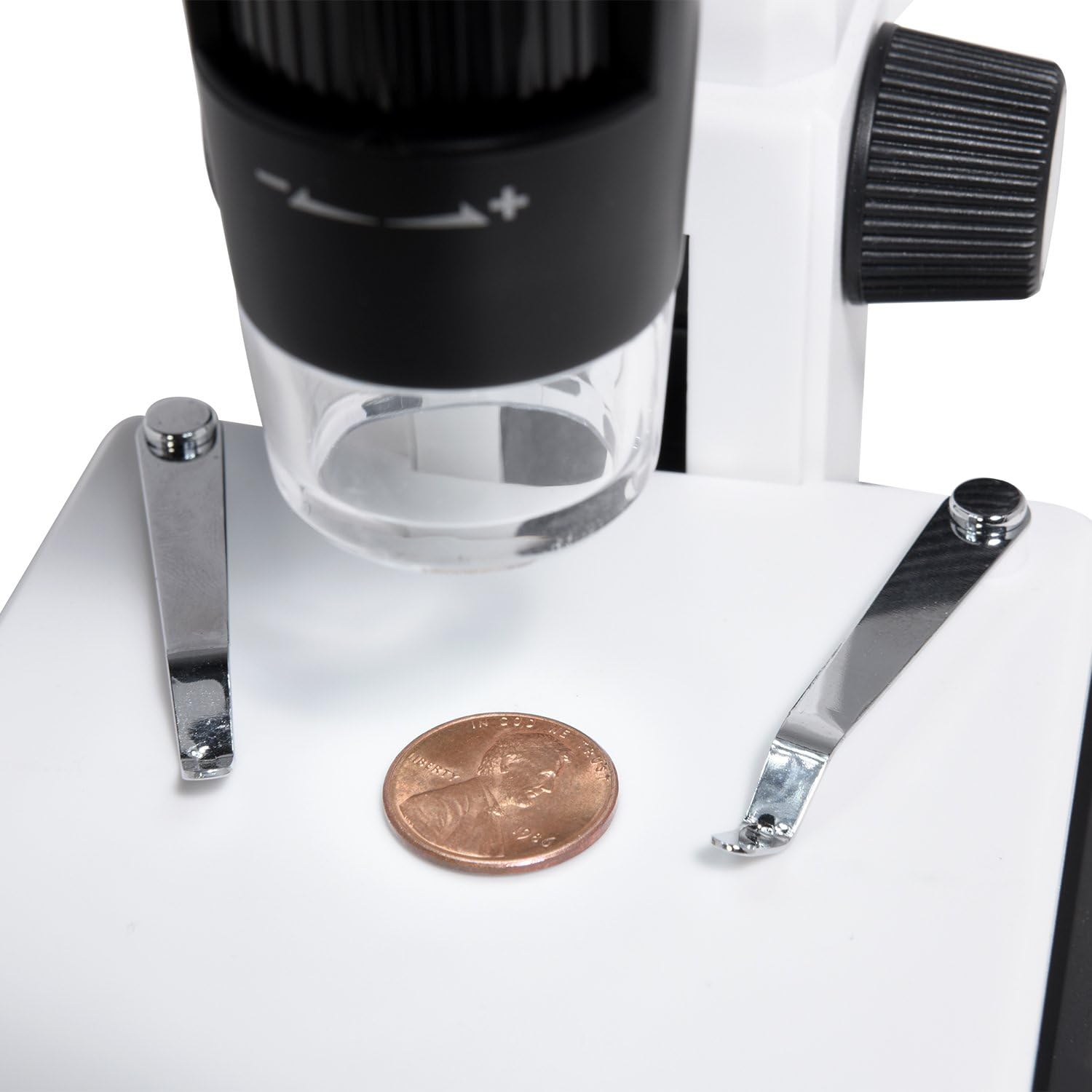 A penny placed on the adjustable stage for microscopic examination.