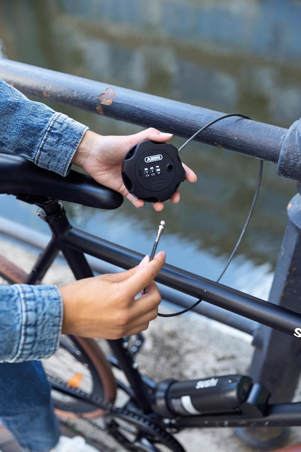 Person securing a bicycle with the ABUS Combiflex Adventure Cable Lock