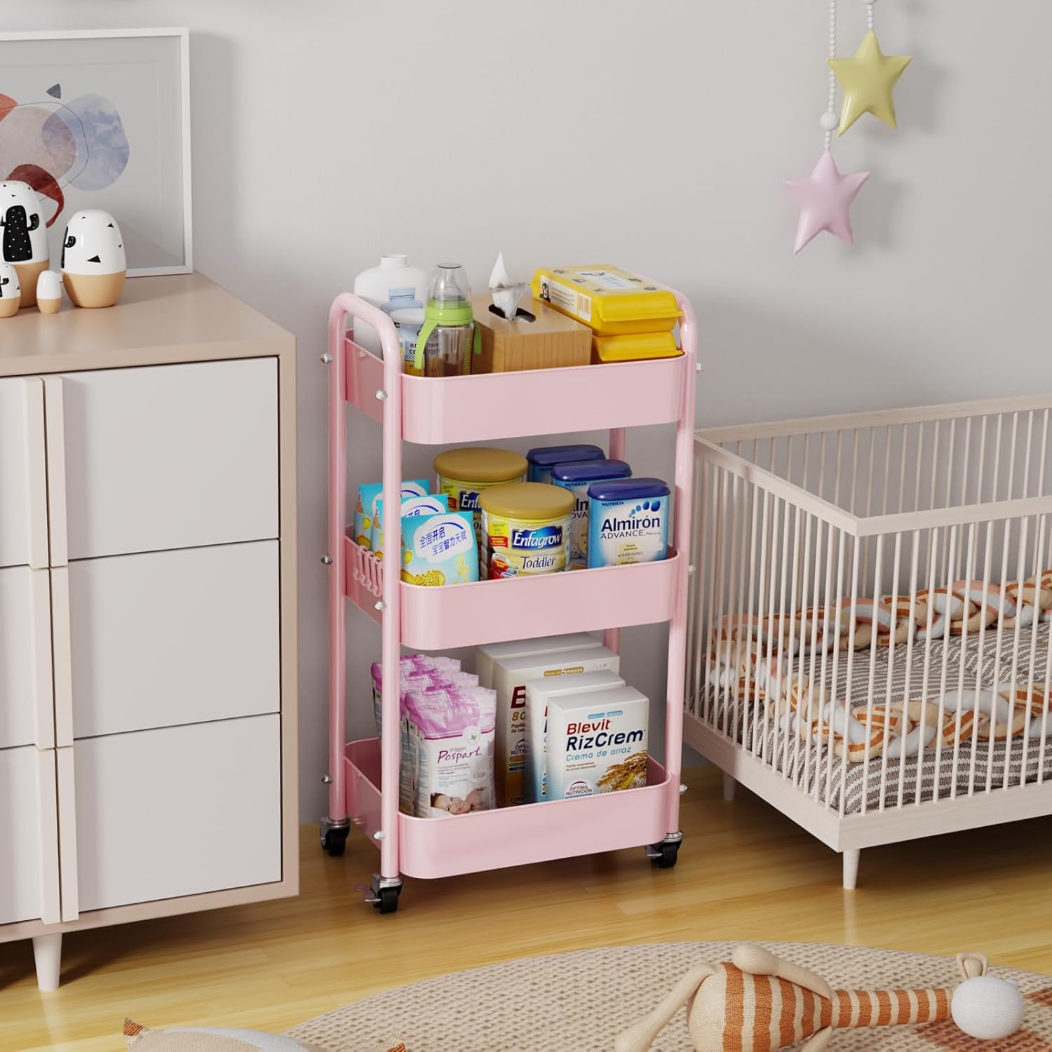 Pink utility cart holding baby supplies in a nursery