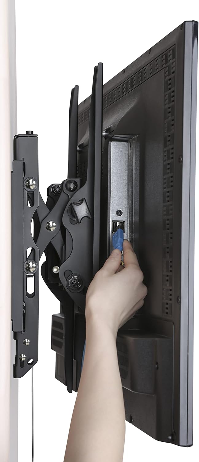 A hand reaching behind a mounted TV to connect a cable, demonstrating easy access to ports.