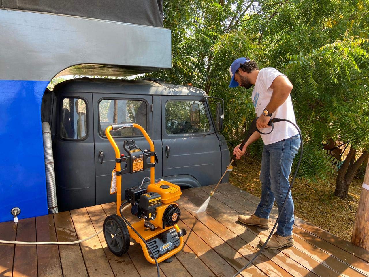 A person operating the INGCO GHPW2003 pressure washer to clean a vehicle