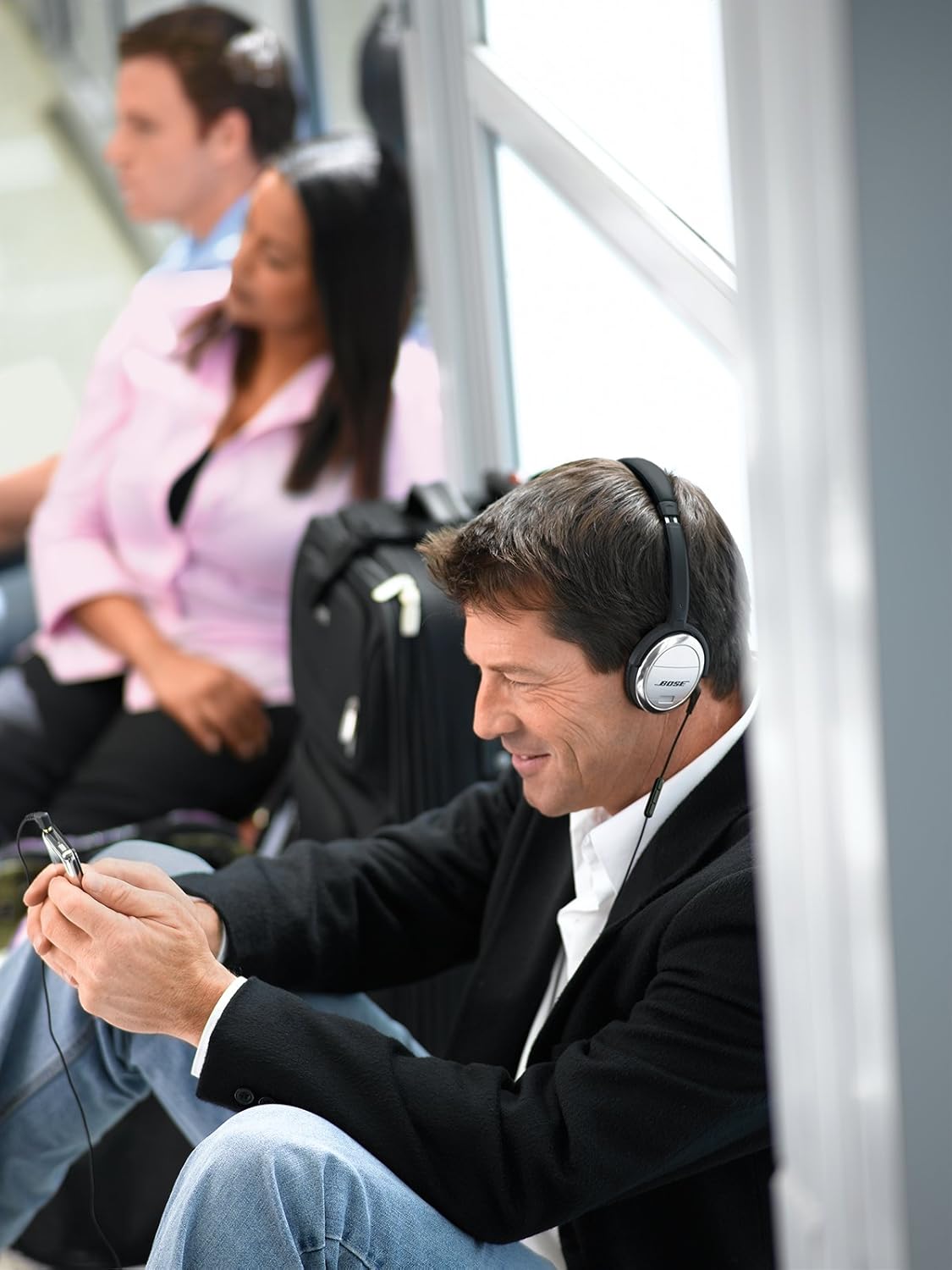 Man wearing Bose QuietComfort 3 headphones while using a mobile device