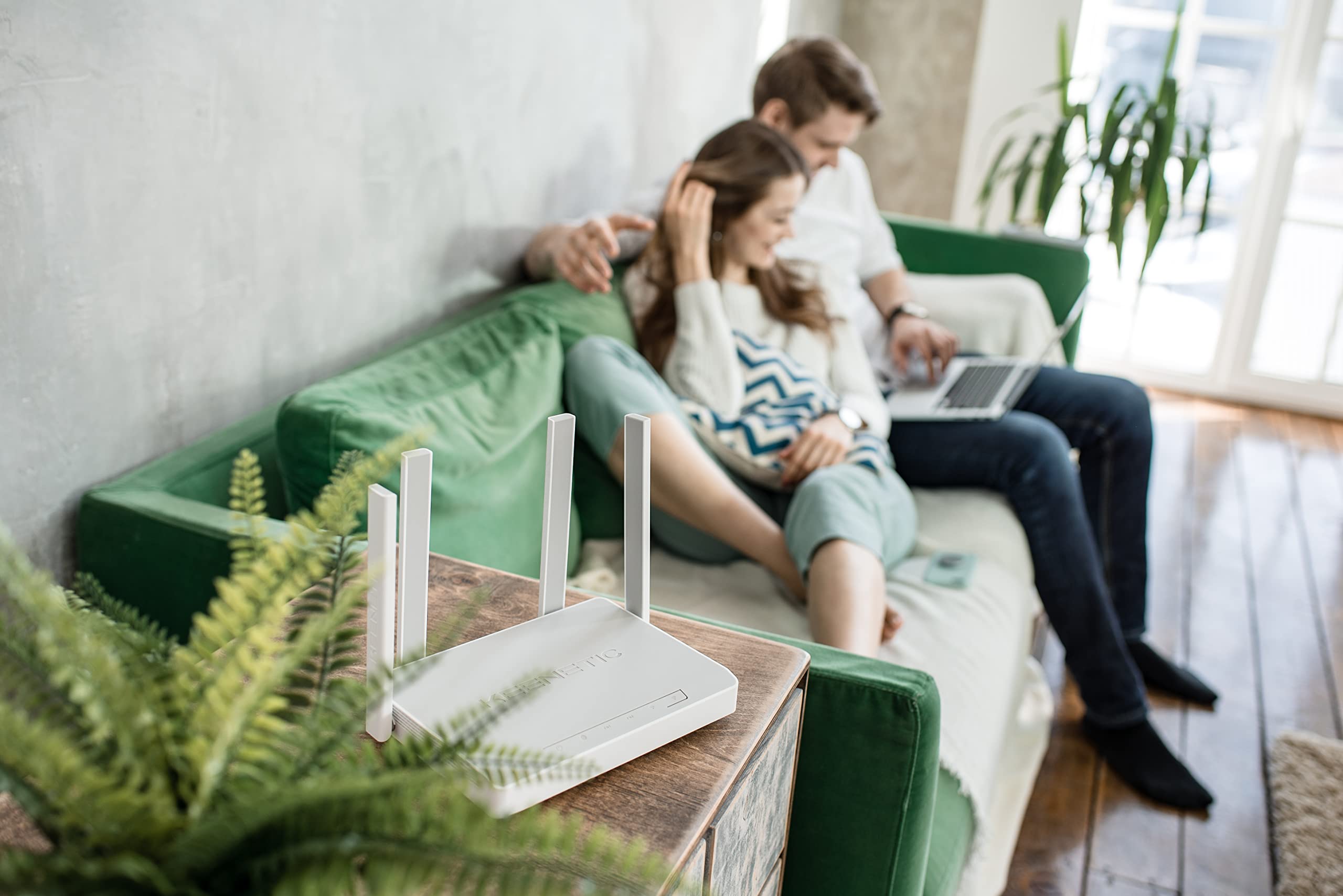 Keenetic Sprinter AX1800 router mounted vertically on a wall next to a vase.