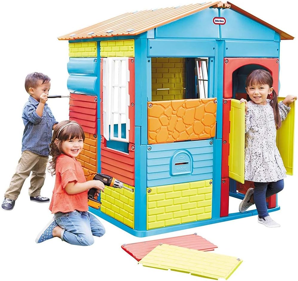 Three children and an adult assembling the colorful panels onto the playhouse frame in a grassy backyard.