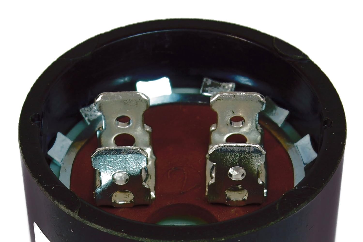 Top-down view into the opening of a TEMCo CD60 Start Capacitor, showing the two quick disconnect terminals and the internal brown insulating material.