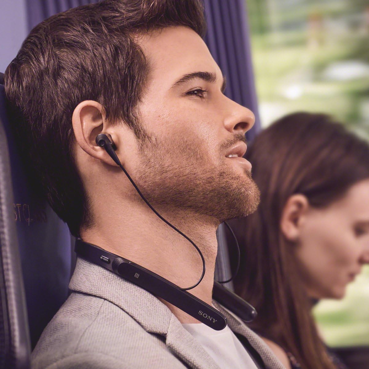 Person wearing Sony WI-1000X headphones on an airplane, demonstrating the behind-neck design.