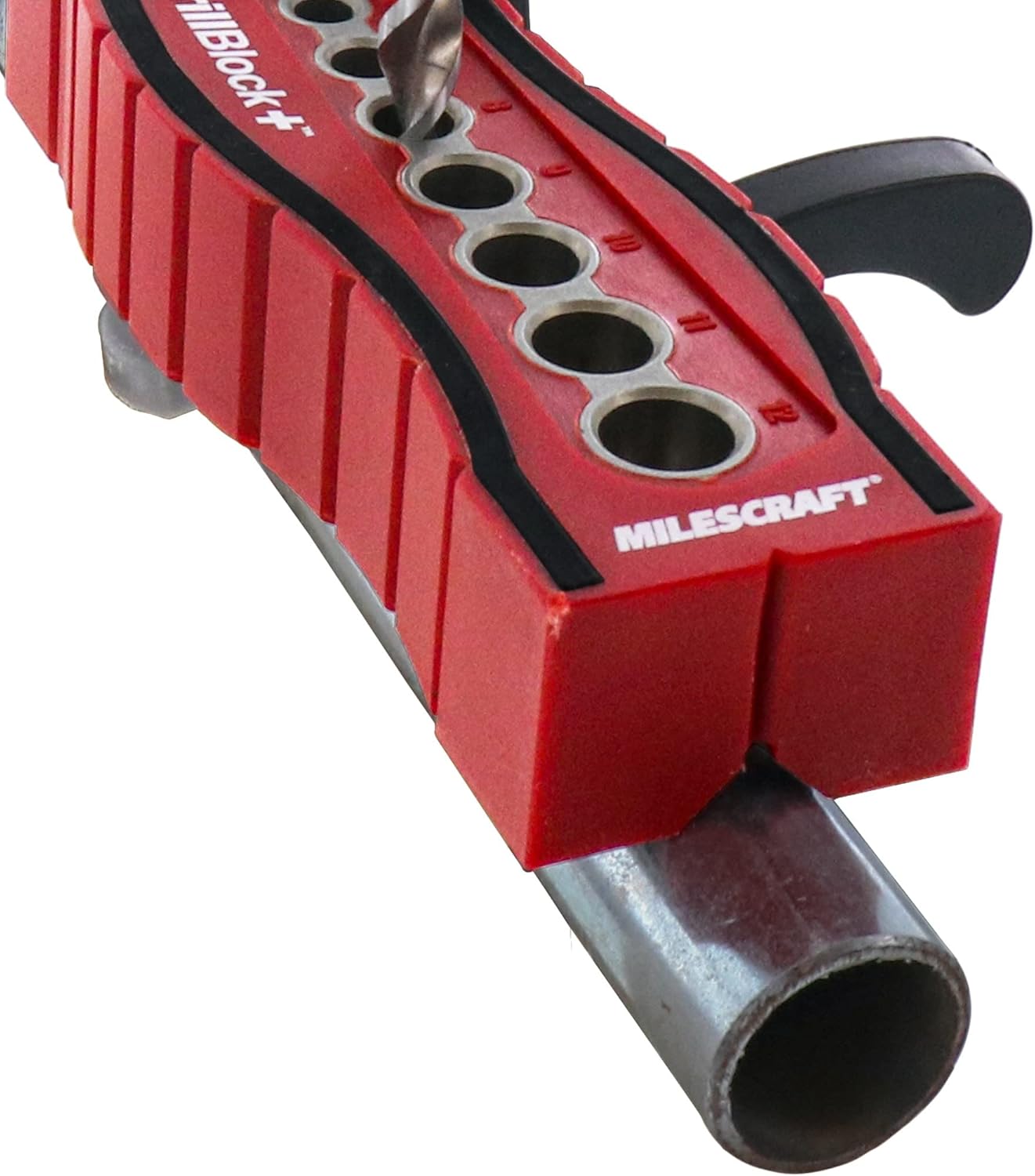 Milescraft DrillBlock+ positioned on a metal pipe, with a drill bit inserted into a guide hole.
