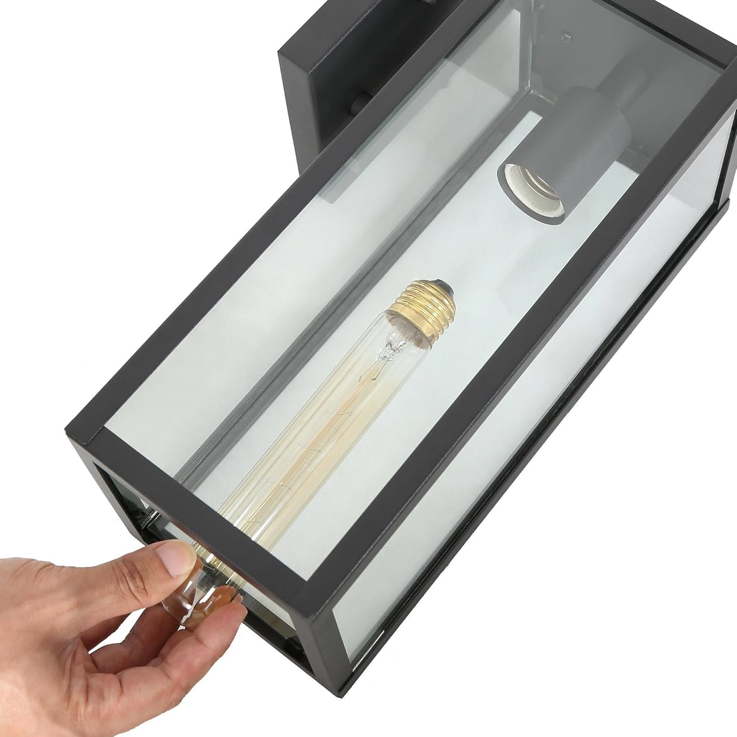 Hand installing an E26 bulb into the open bottom of the outdoor wall light