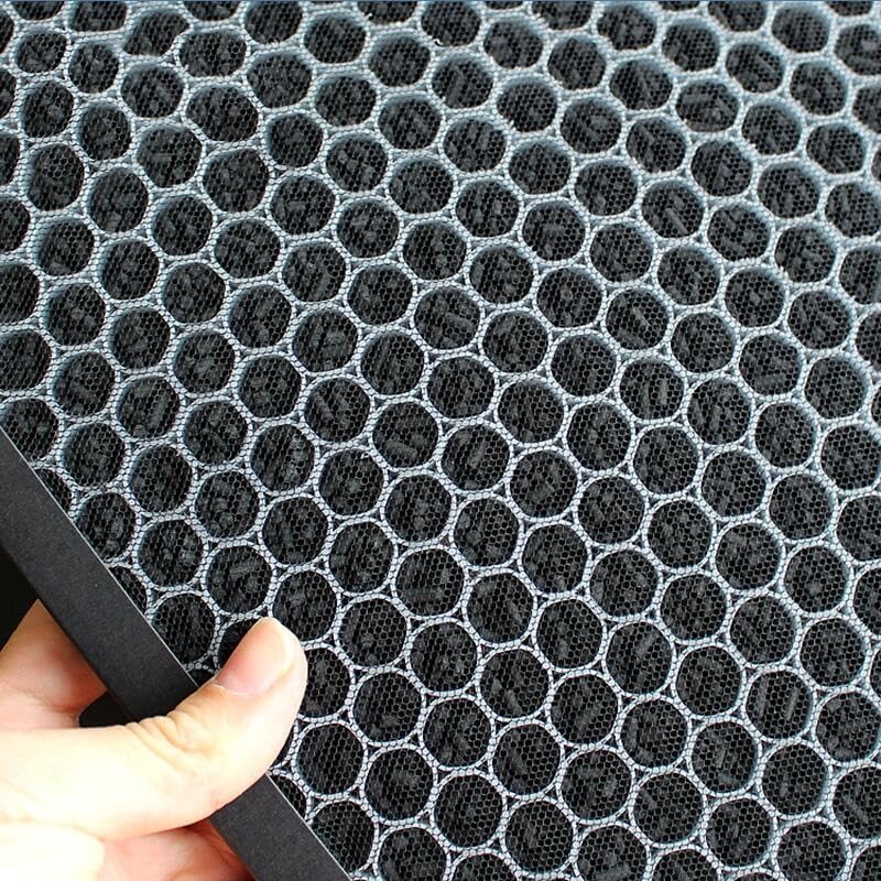 A hand holding a black honeycomb-patterned activated carbon filter, highlighting its structure.