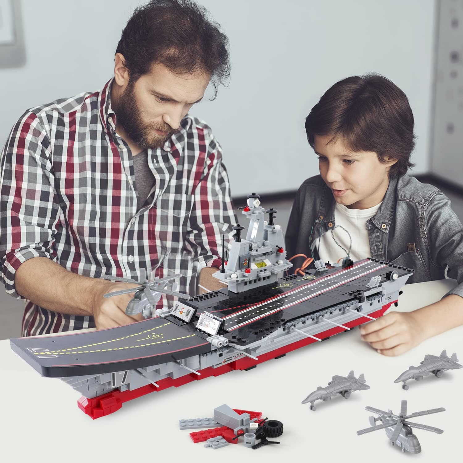 Image showing a father and son collaboratively assembling the military aircraft carrier building blocks set on a table.