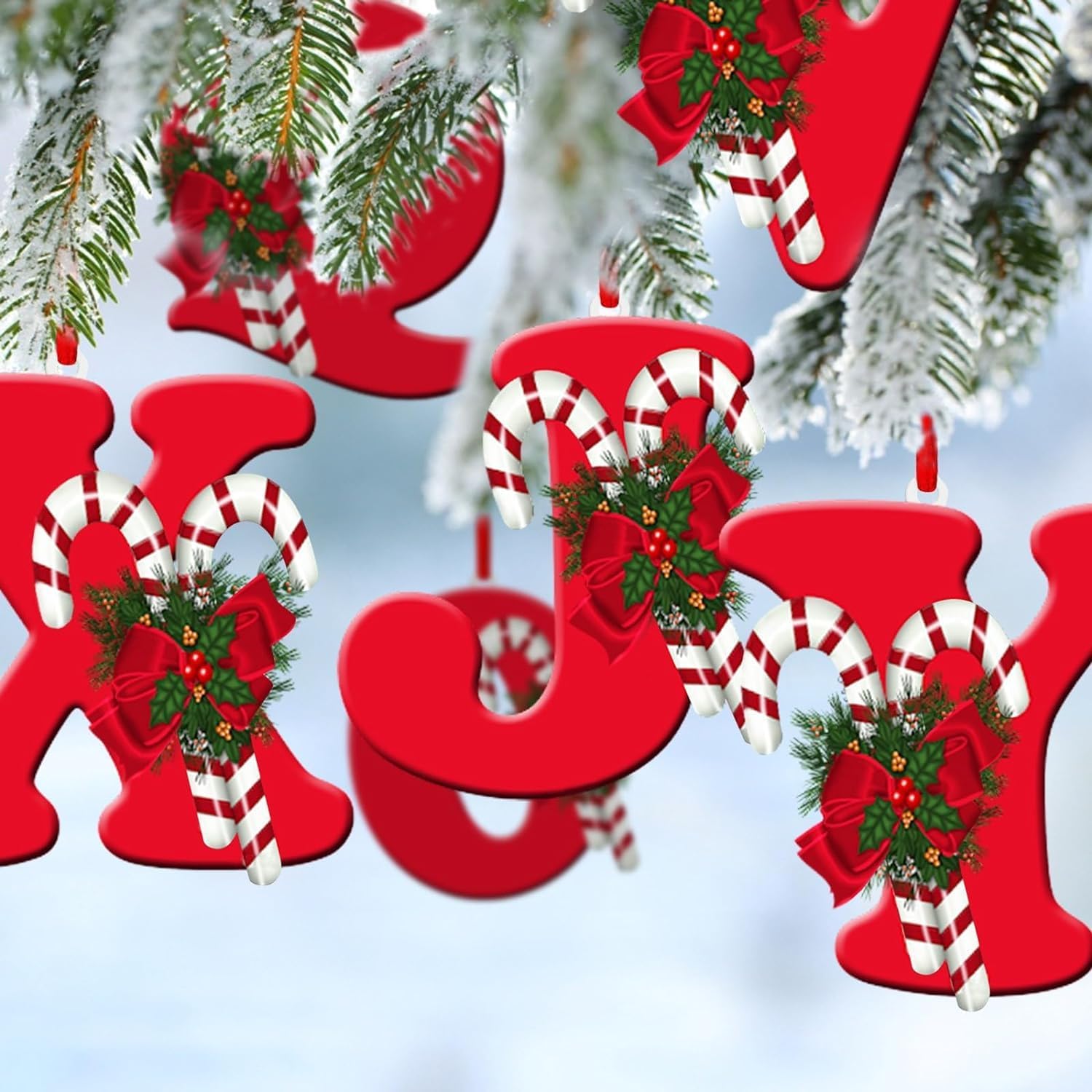 Multiple red letter Christmas ornaments hanging on a snow-dusted Christmas tree, spelling out 'JOY'.