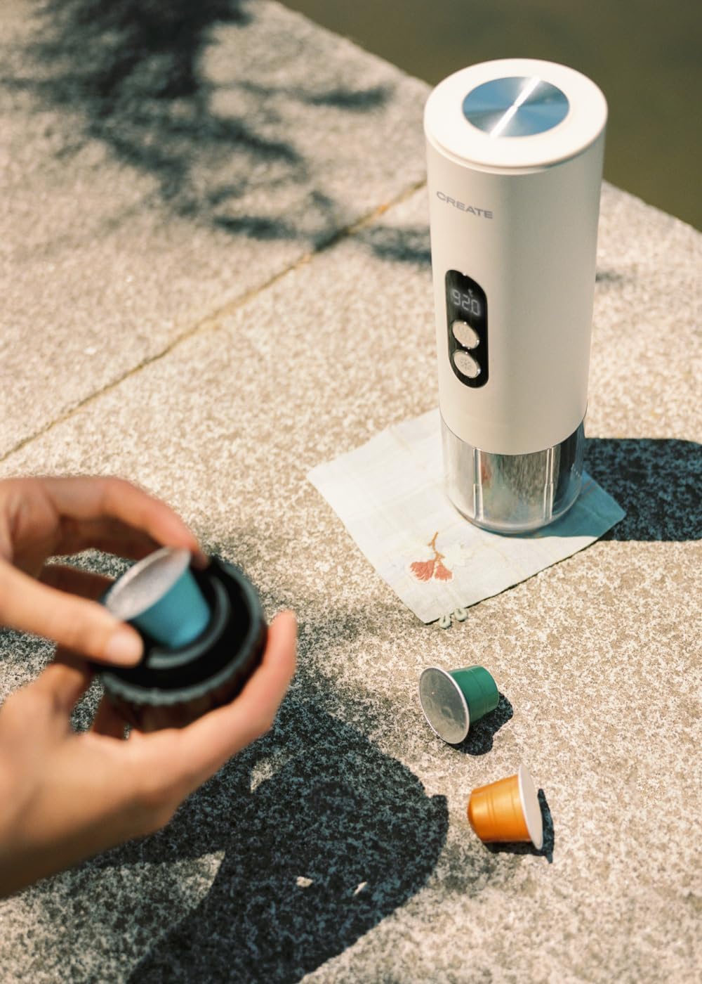 A hand inserting a blue coffee capsule into the capsule adapter of the CREATE THERA MOVE machine.