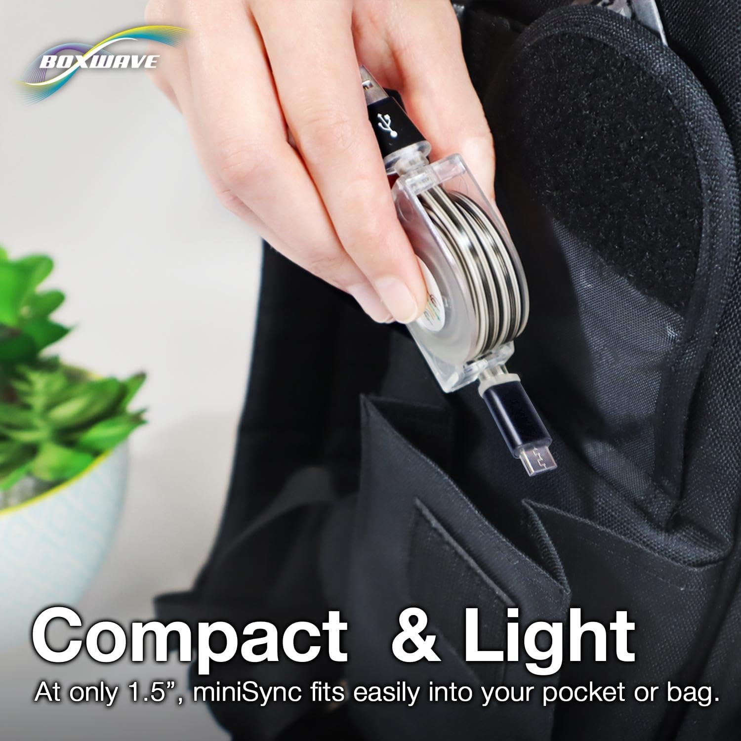 A hand placing the compact BoxWave miniSync retractable cable into a bag.