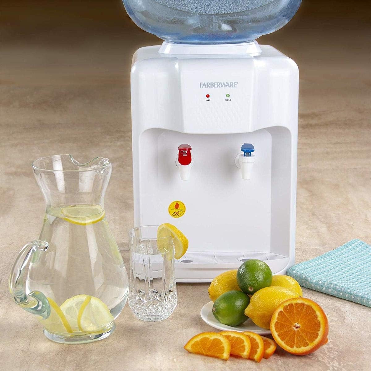 Farberware FW-WD211 water dispenser on a countertop with a pitcher of lemon water, a glass, and fresh citrus fruits.