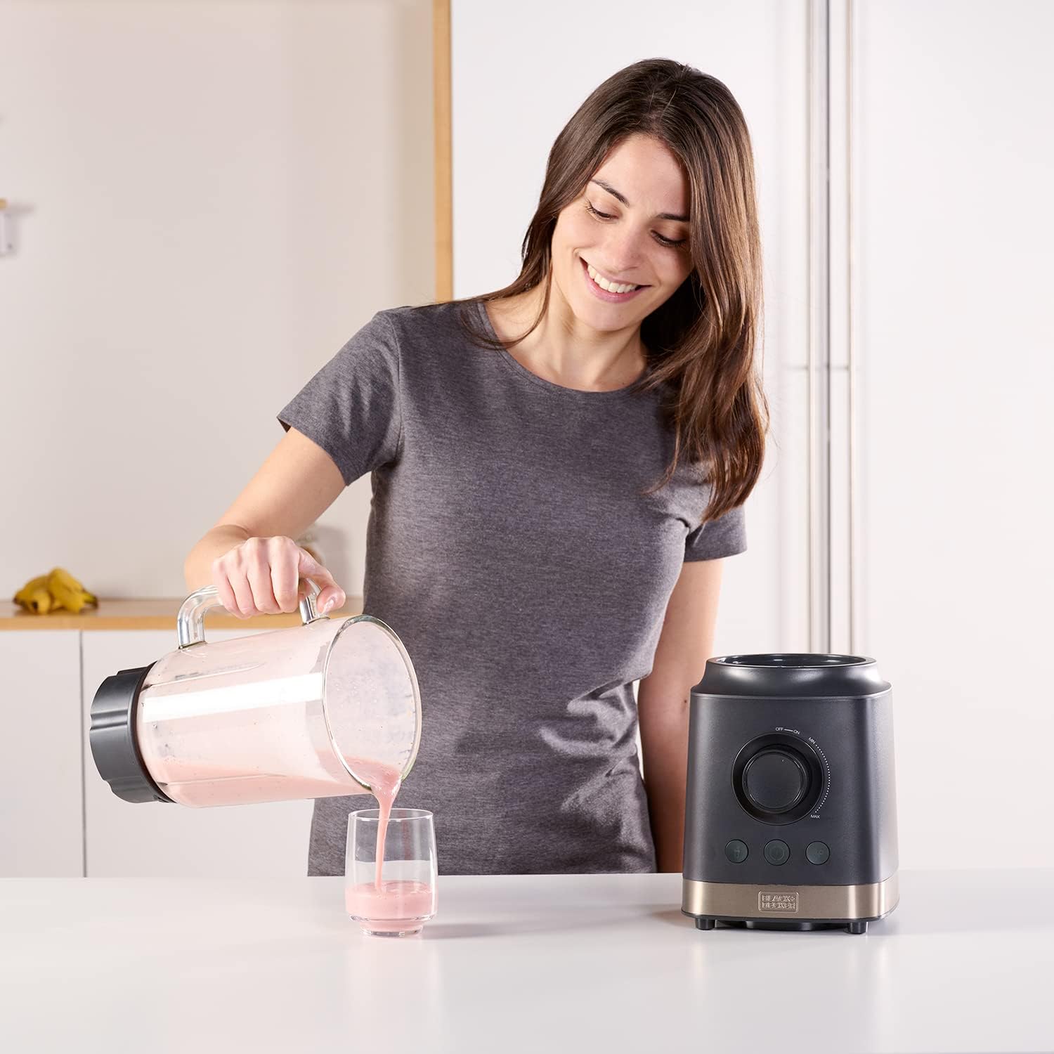 Woman pouring blended smoothie from blender jar into a glass