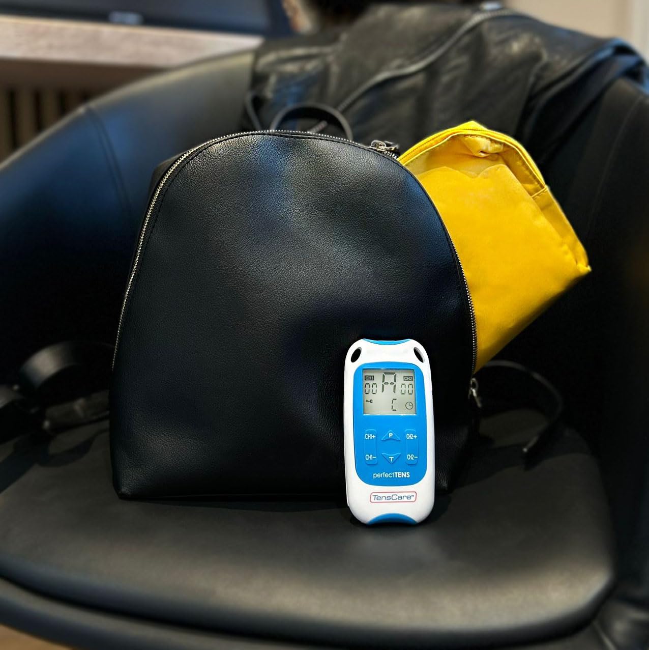 Image showing the TensCare Perfect TENS unit next to a yellow soft storage pouch, indicating portability.