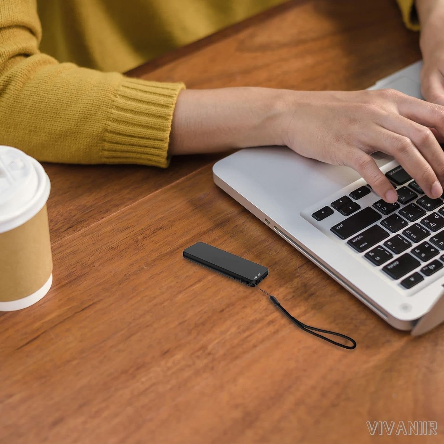 Vivaniir 60H Digital Voice Recorder placed next to a laptop with a person typing