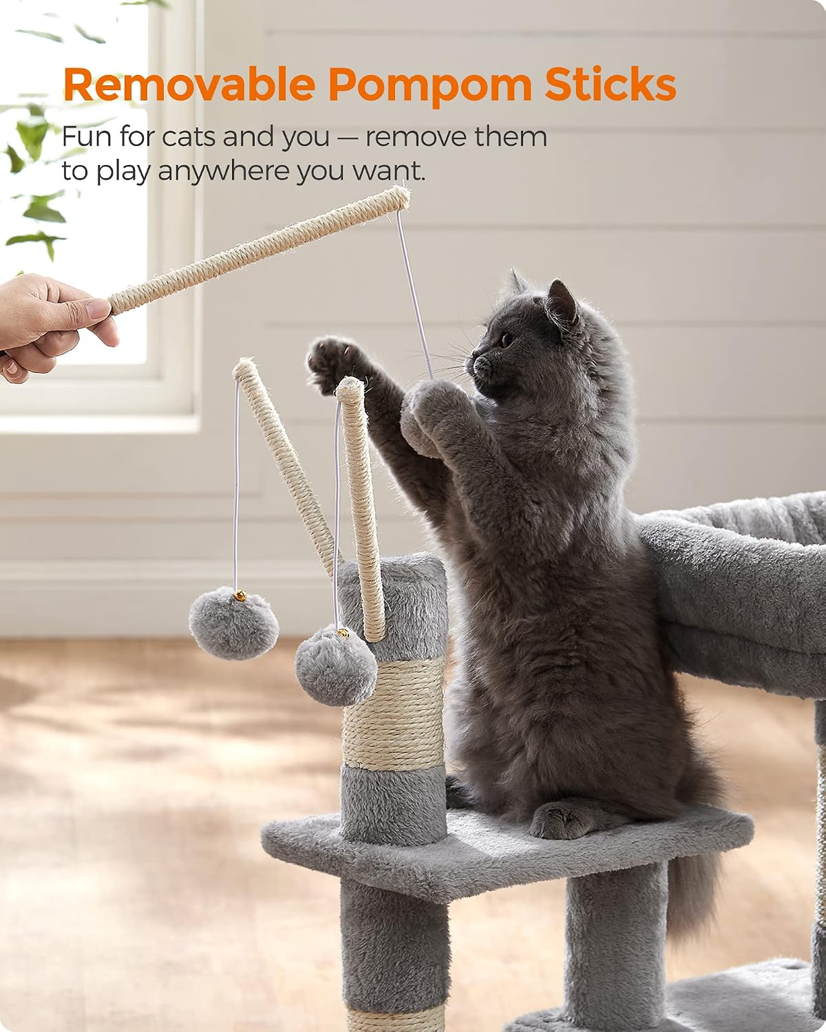 A grey cat playing with a removable pompom stick from the Feandrea Cat Tree, demonstrating interactive play.
