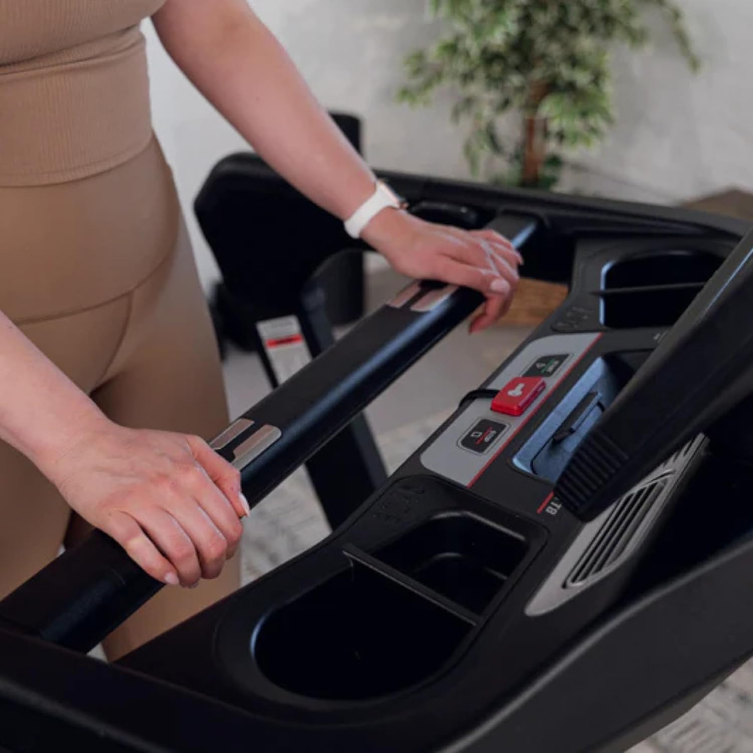 A person's hands adjusting the controls on the SOLE TT8 Treadmill's handrail.