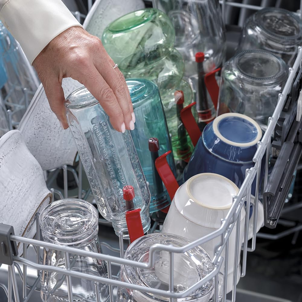 A hand placing a bottle onto the bottle jets in the GE dishwasher's upper rack.