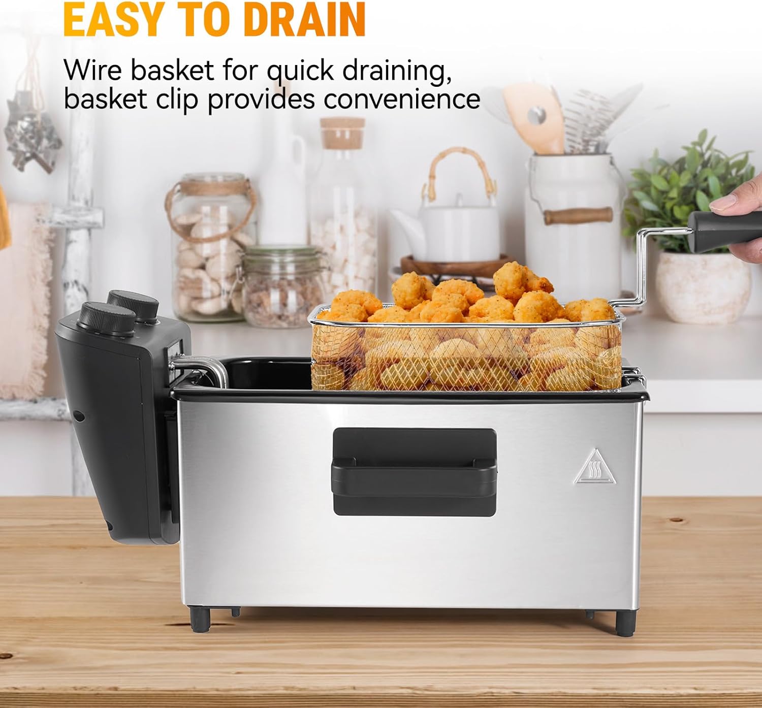 A frying basket filled with food is hooked onto the side of the deep fryer, allowing oil to drain.