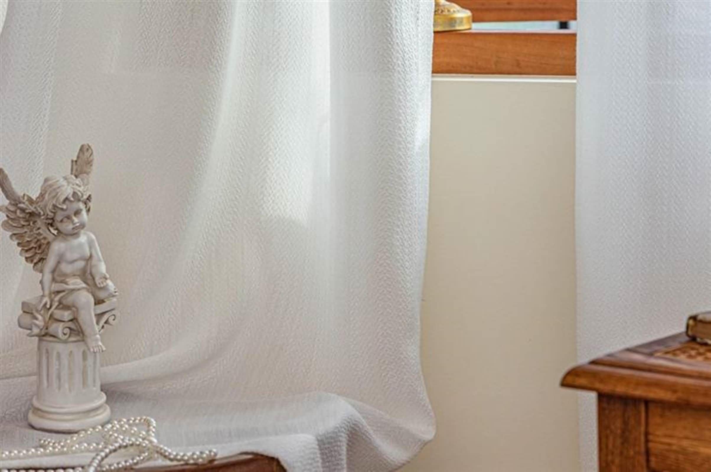 Rideau voilage blanc à œillets avec délicats motifs feuilles pour une chambre lumineuse