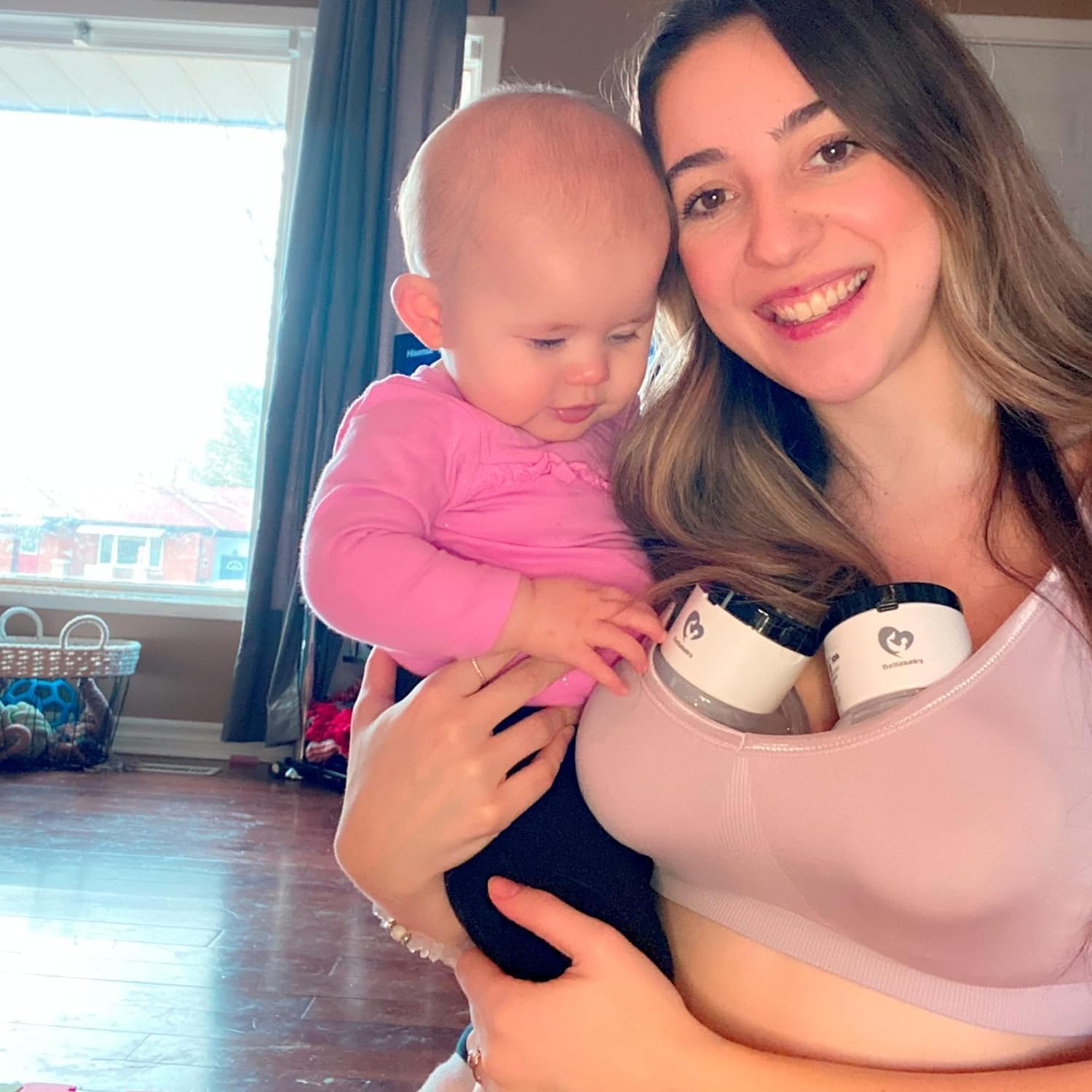 Woman using Bellababy wearable breast pumps while holding a baby
