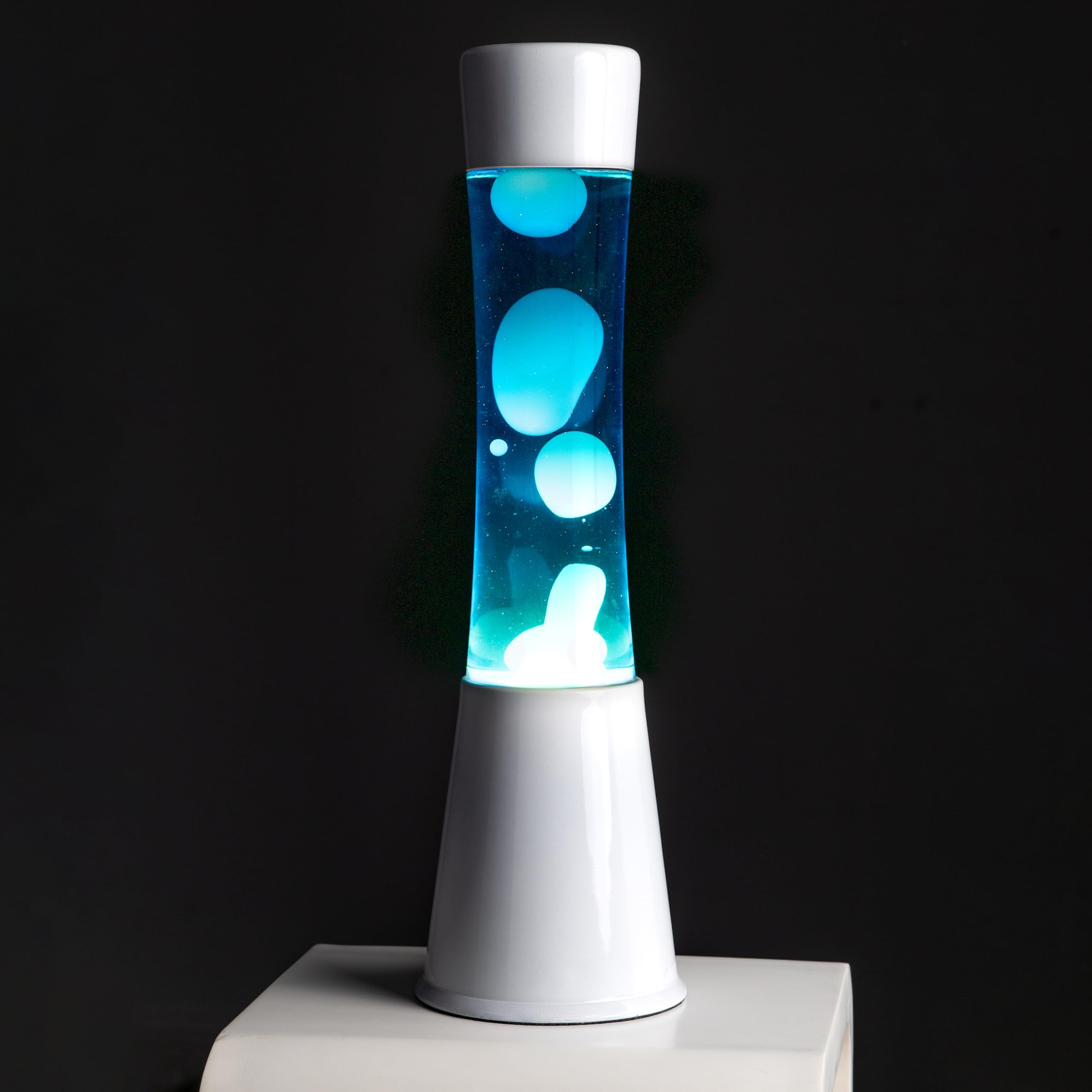 Fisura - Lámpara de lava blanca y azul años 70. Base color blanco, líquido azul y lava blanca. Lámpara efecto relajante. Medidas: 11 cm x 11cm x 39,5 cm.
