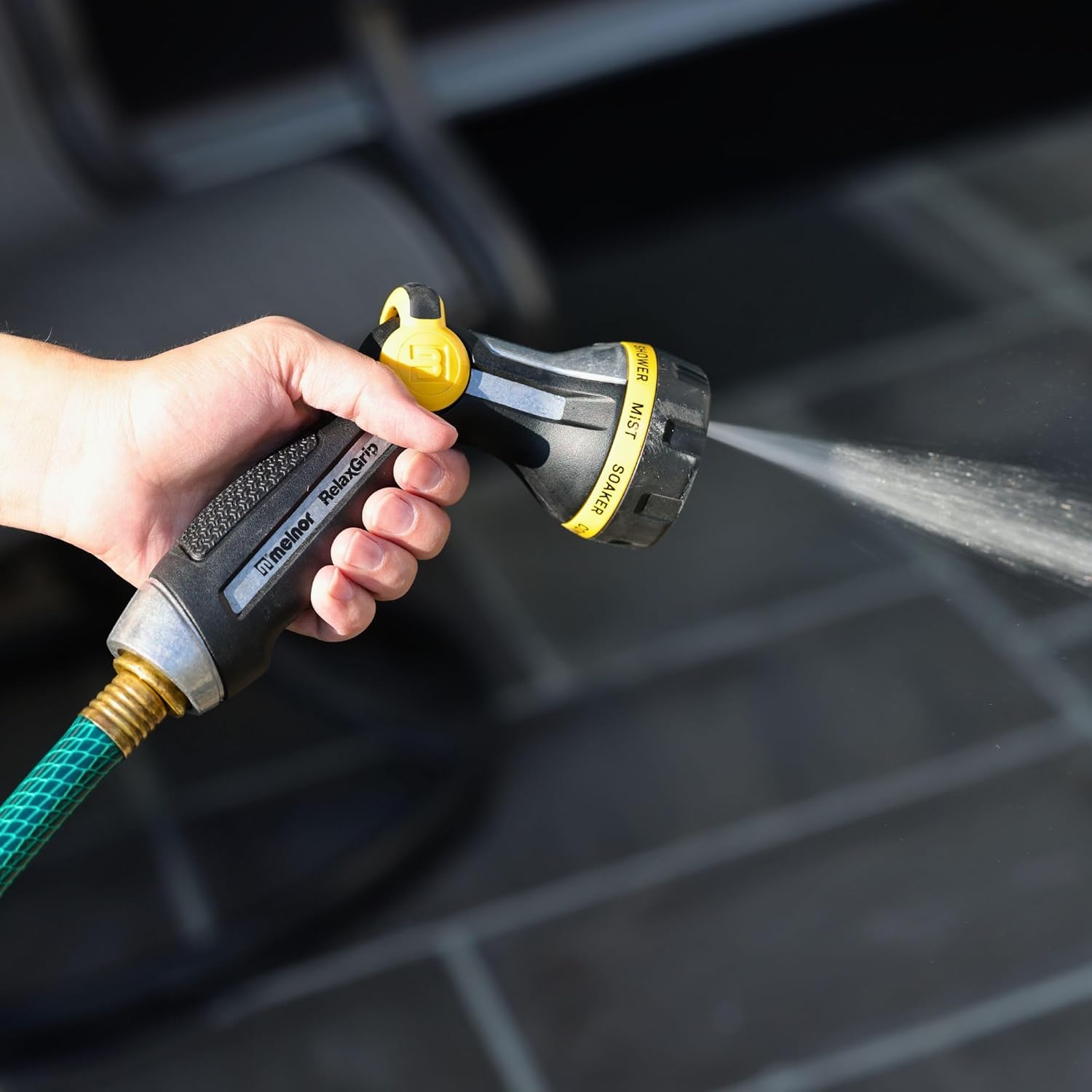 Hand holding Melnor RelaxGrip nozzle spraying water in a mist pattern