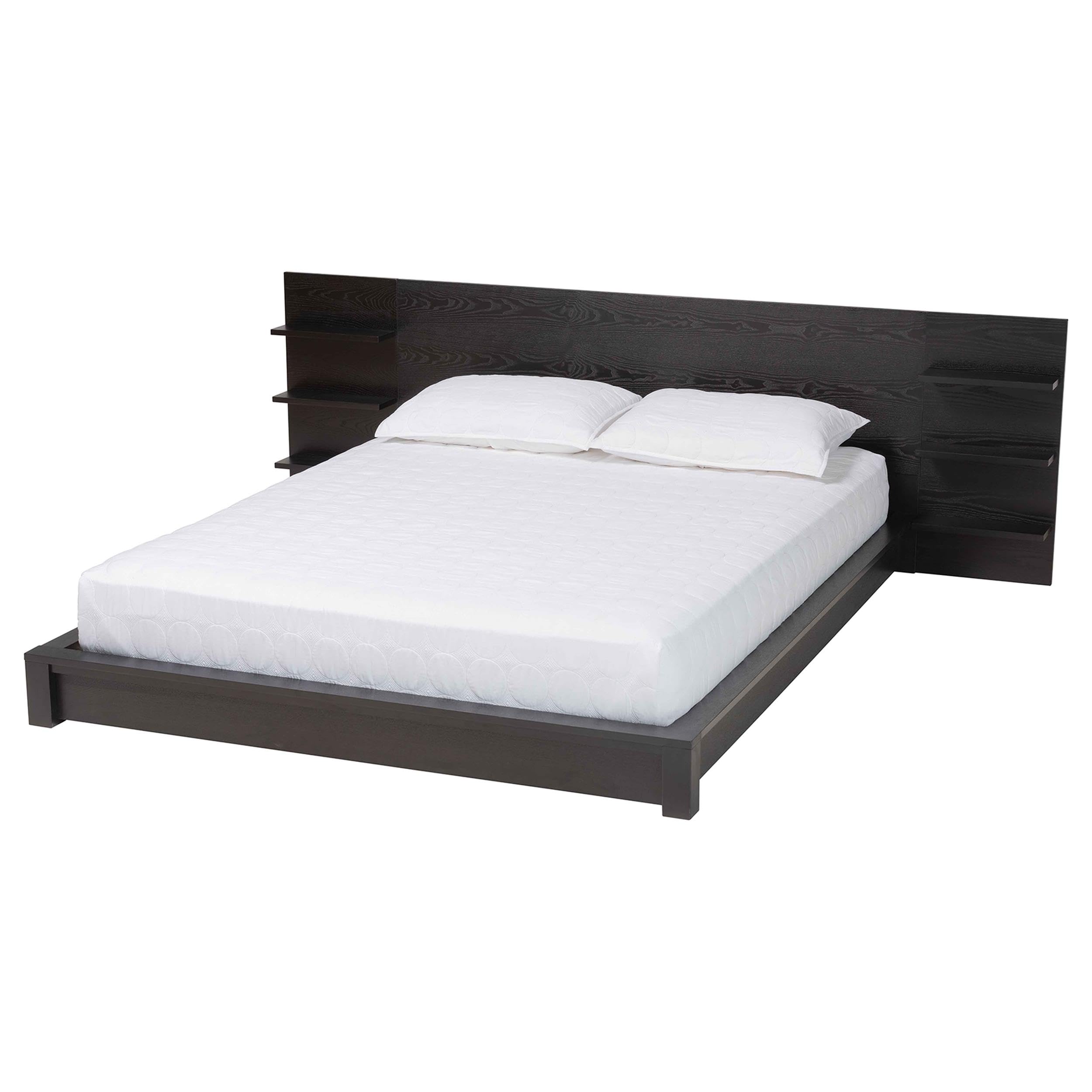A fully assembled Baxton Studio Elina Queen Platform Bed with a mattress and bedding, showcasing the black wood finish and the headboard with built-in shelves in a modern bedroom setting.