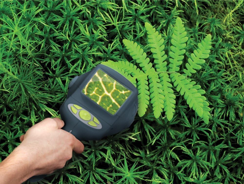 Ruka držící kameru EyeClops BioniCam nad zelenou rostlinou, zobrazující zvětšenou view povrchu rostliny na obrazovce zařízení.