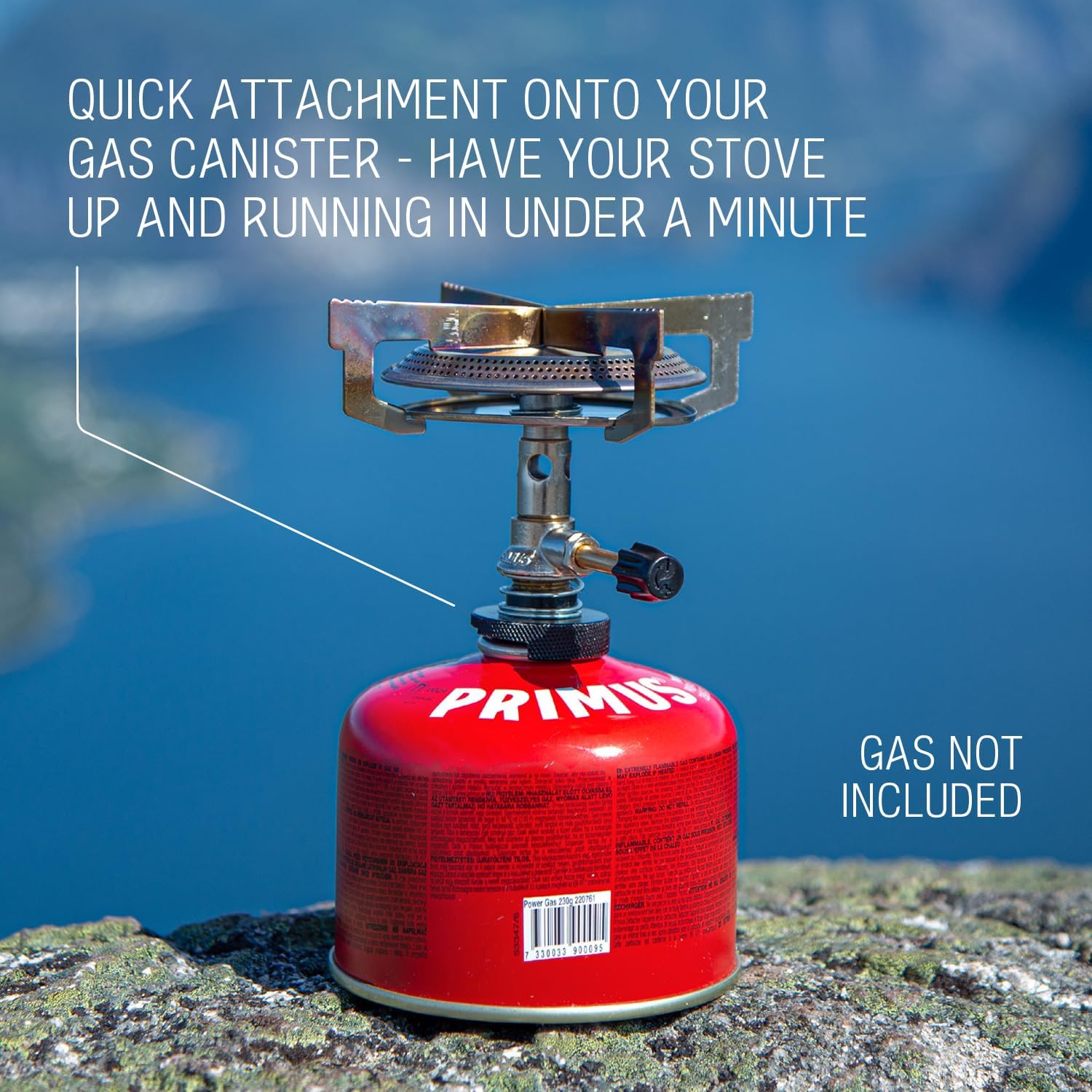 Primus Mimer Gas Stove attached to a red gas canister on a rock with a lake in the background