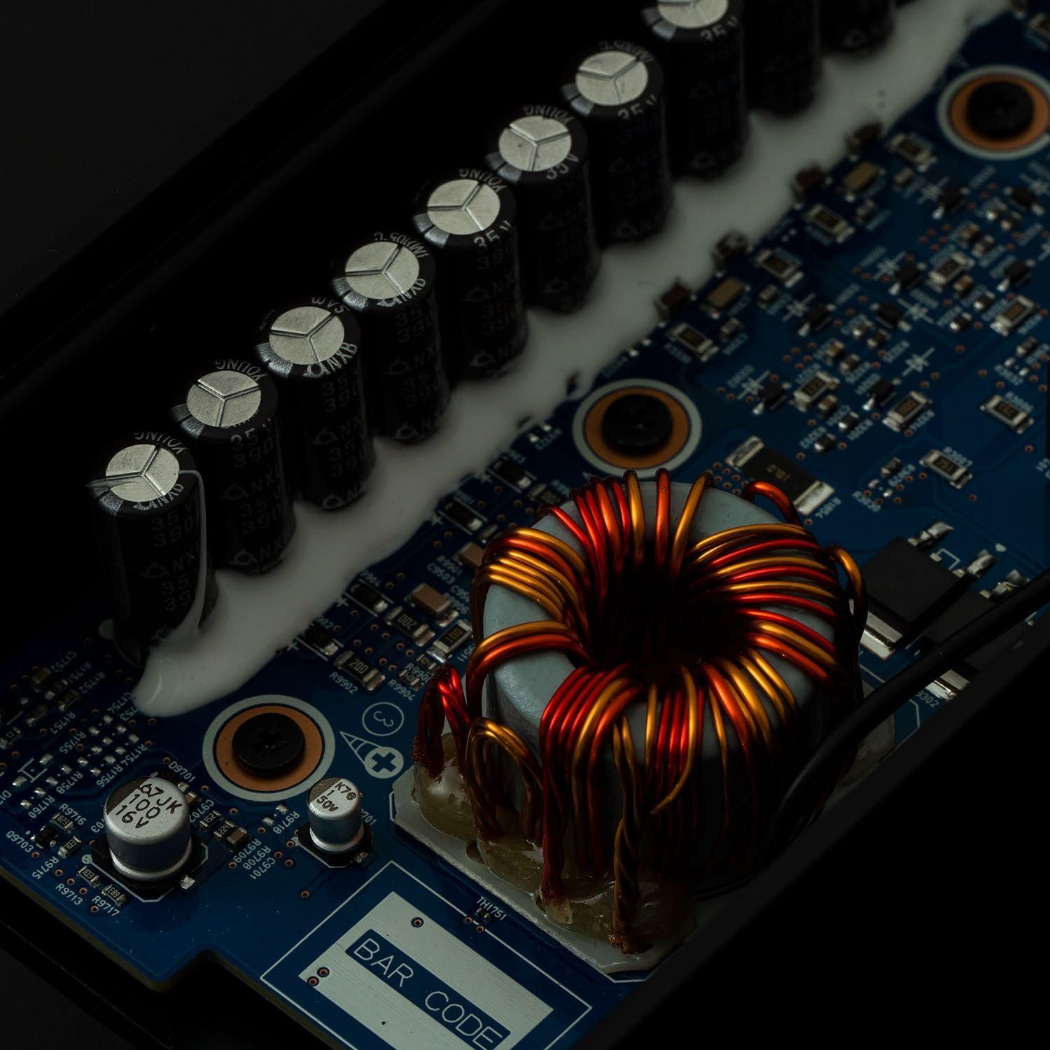 Internal circuit board of the Alpine KTP-600 amplifier, showing capacitors and a toroidal inductor.