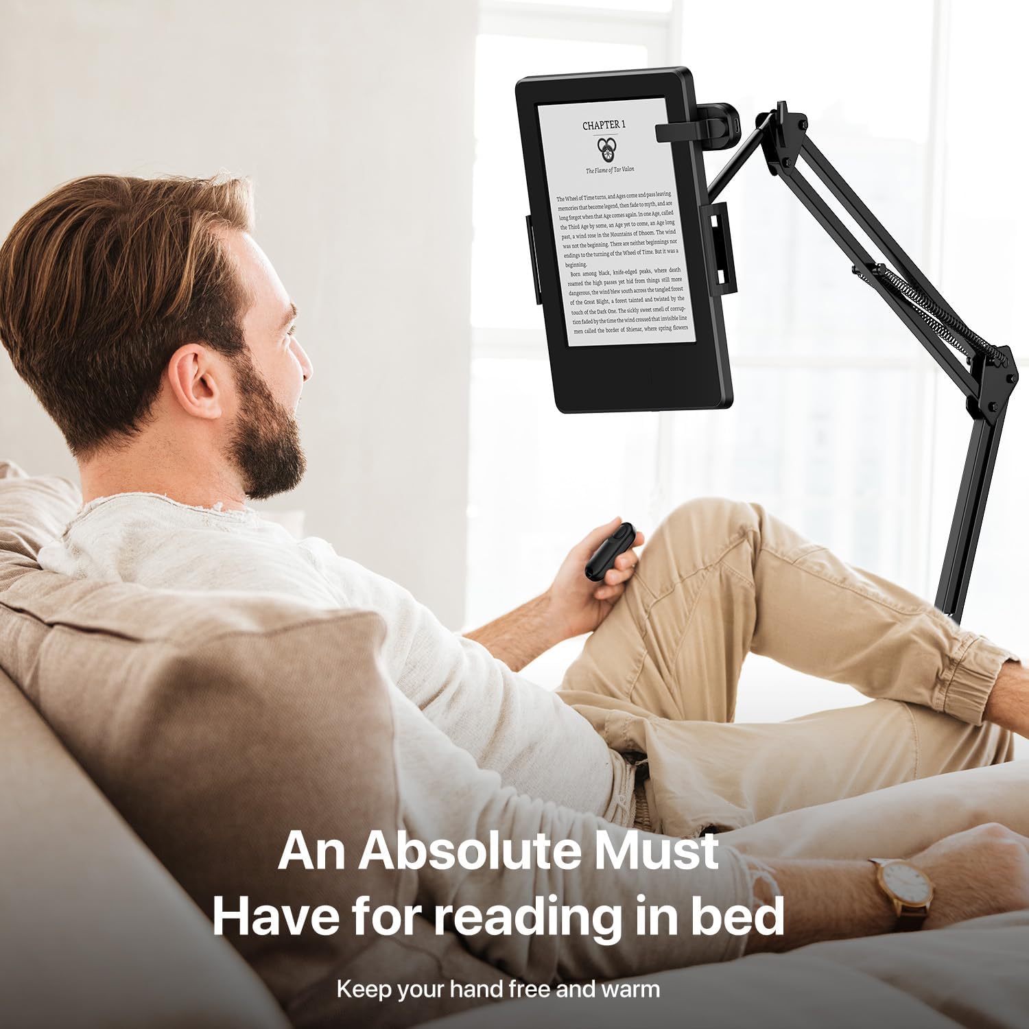 Man comfortably reading an e-reader mounted on a stand, using the remote page turner.