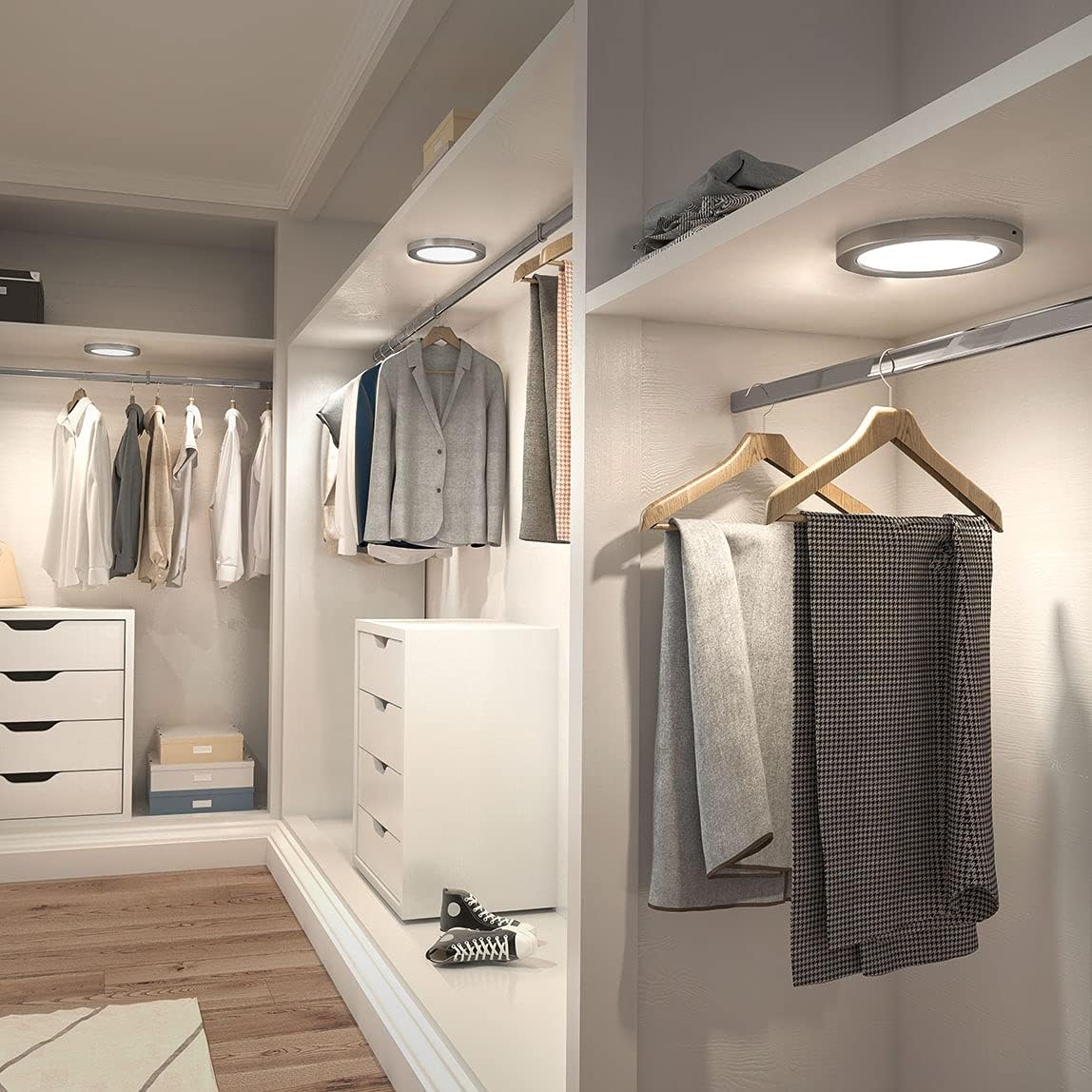 Two artika Lumo LED lights installed on the ceiling of a modern closet, illuminating clothing and shelves.