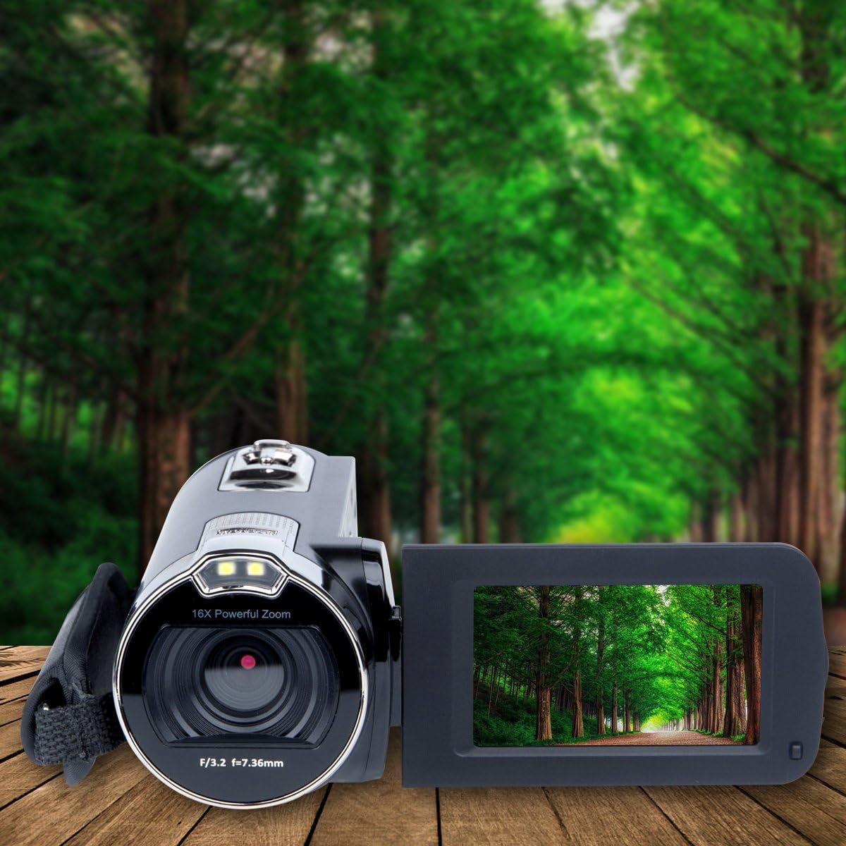 Kimire Camcorder on a wooden surface, with its screen open displaying a lush green forest scene, emphasizing its use for capturing outdoor moments.