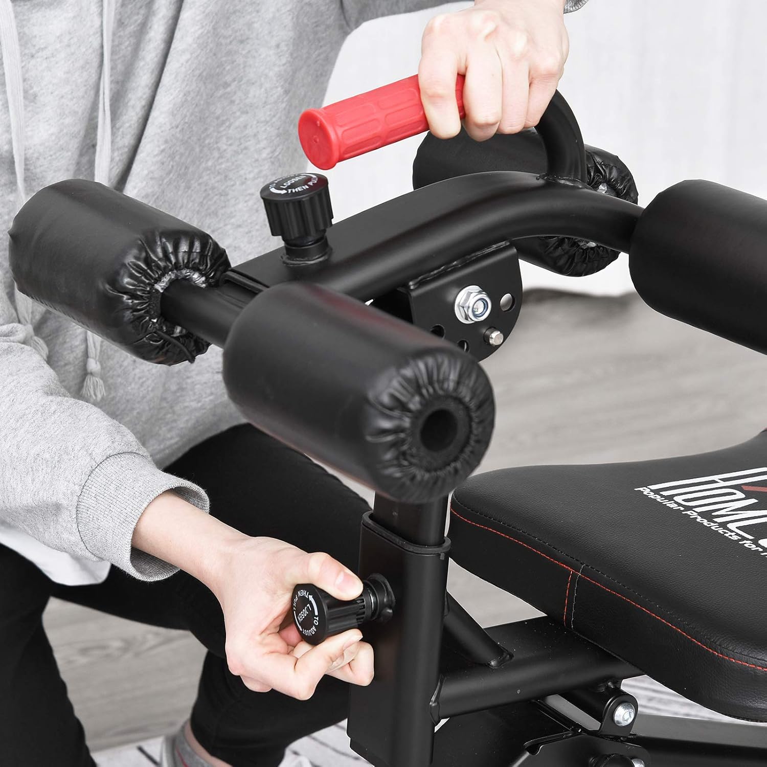 Close-up image showing a hand adjusting the height of the thigh support foam rollers on the HOMCOM weight bench.