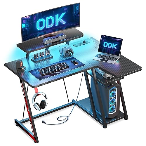 ODK Mesa Gaming 100x70 cm Esquina con Luces LED y Tomas de Corriente, Escritorio Gaming L con Soporte para Monitor, Mesa Gamer con Estante de Almacenamiento Fibra de Carbono Negro - 100 cm