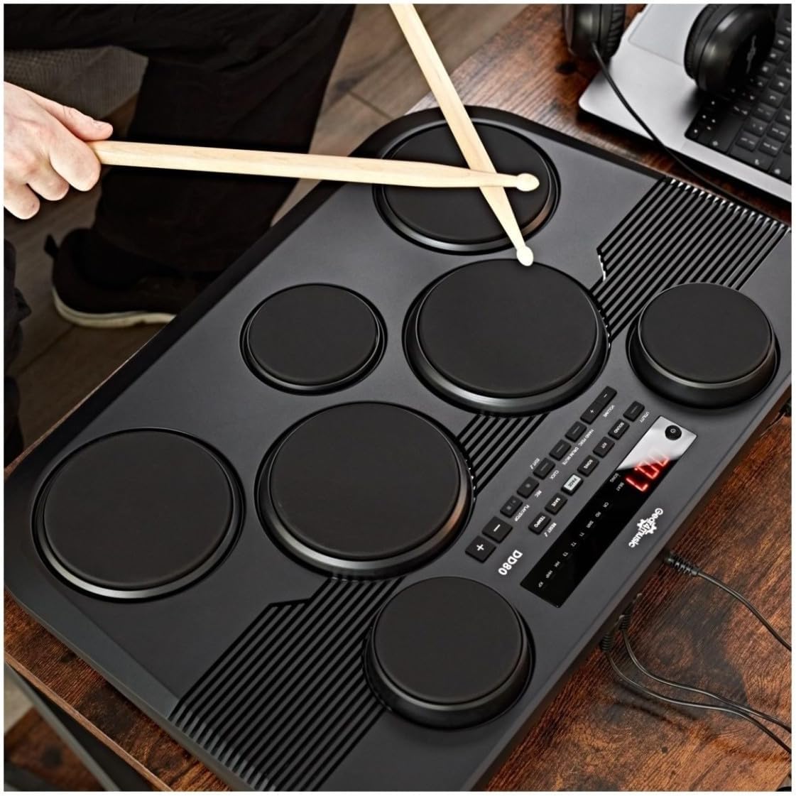 Hands playing the DD80 electronic drum kit with drumsticks