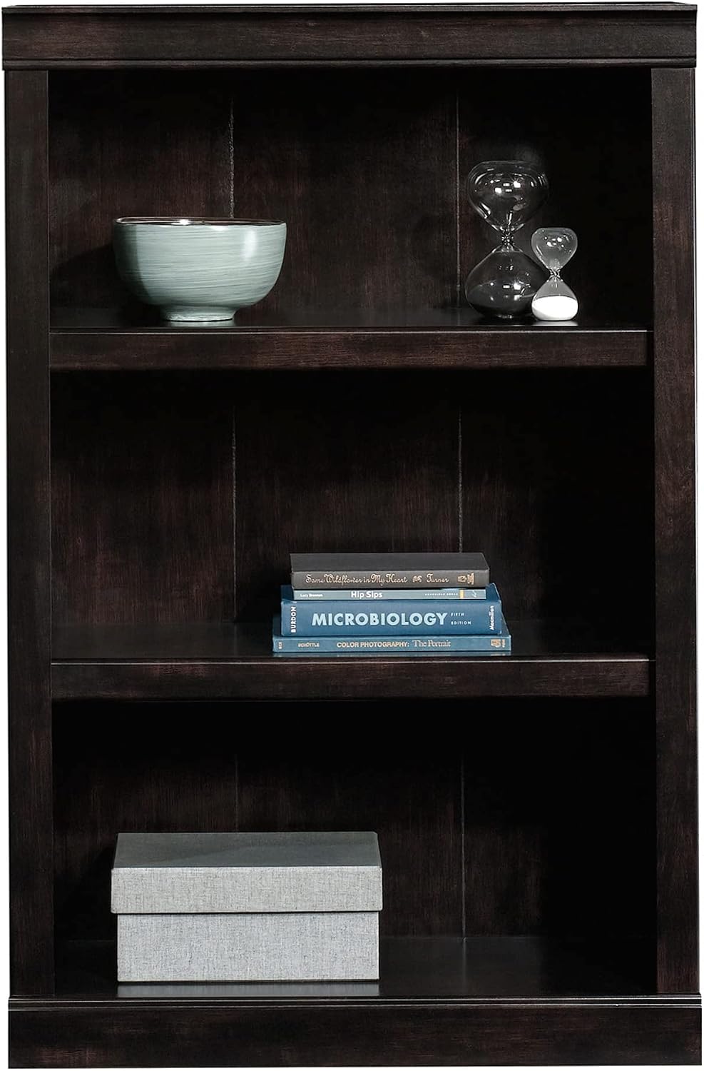Close-up of the middle and bottom shelves of the bookcase, filled with books and a decorative box.
