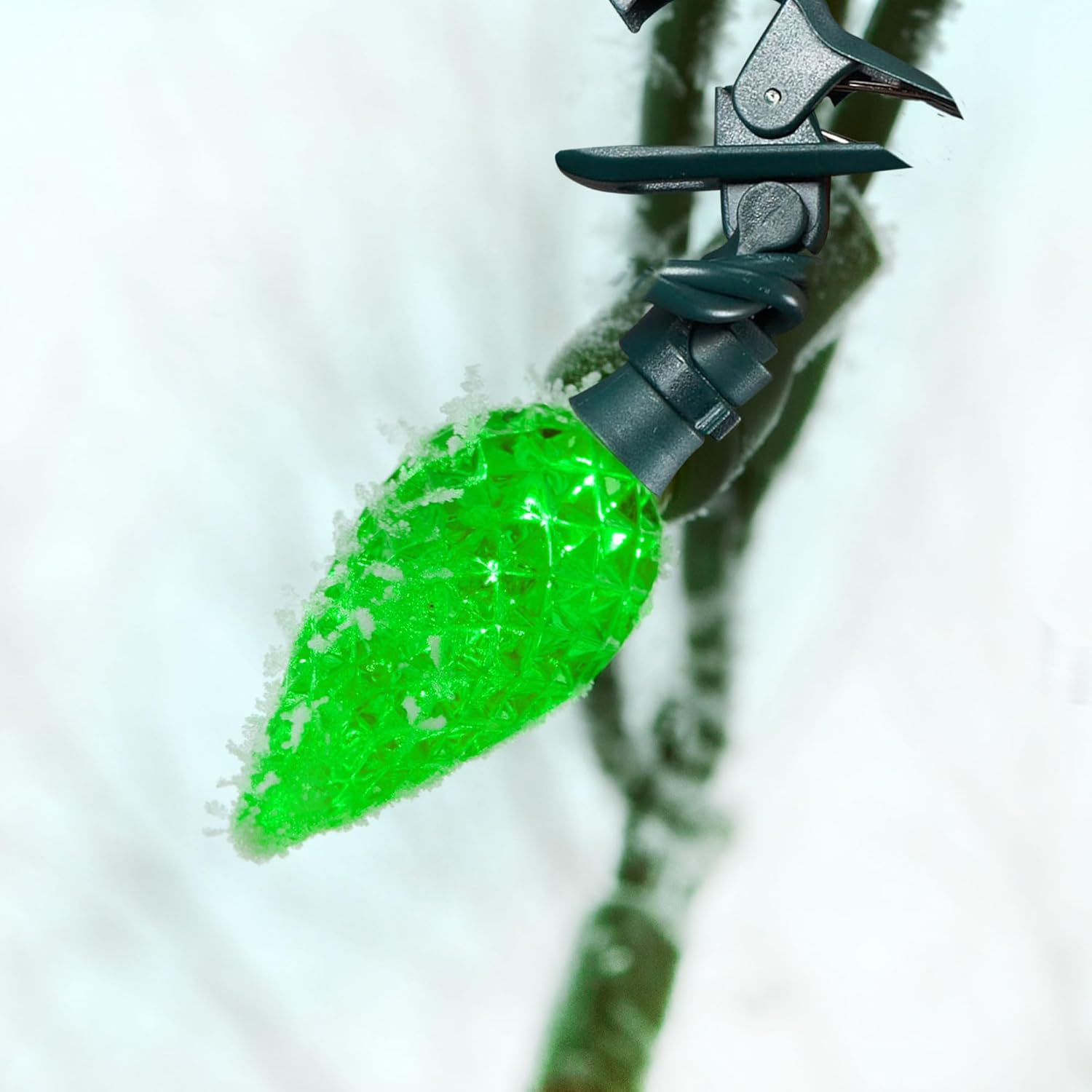 Close-up of a Noma LED light bulb covered in light snow, demonstrating weather resistance.