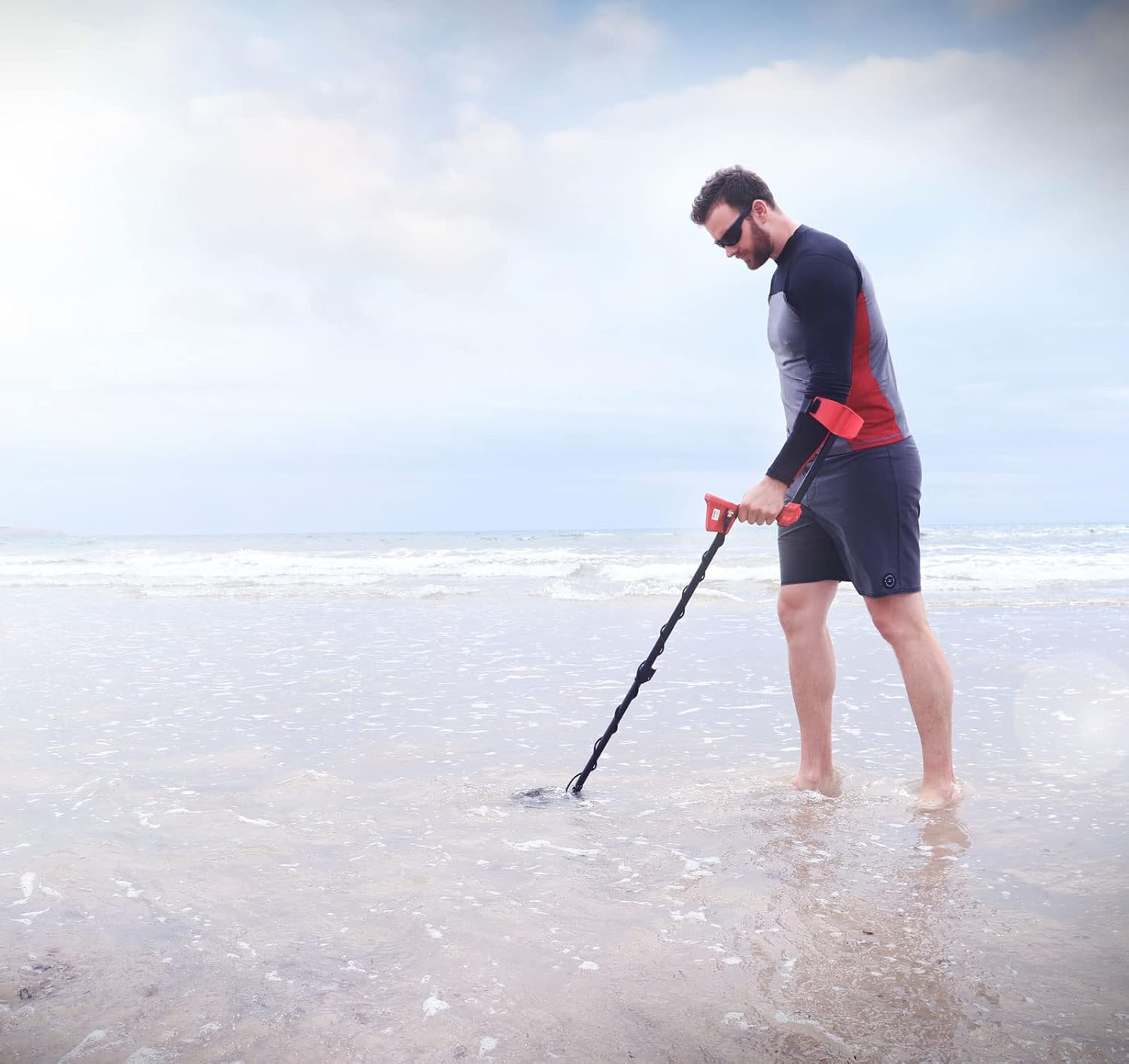 Person using a pinpointer to locate a small object in excavated soil
