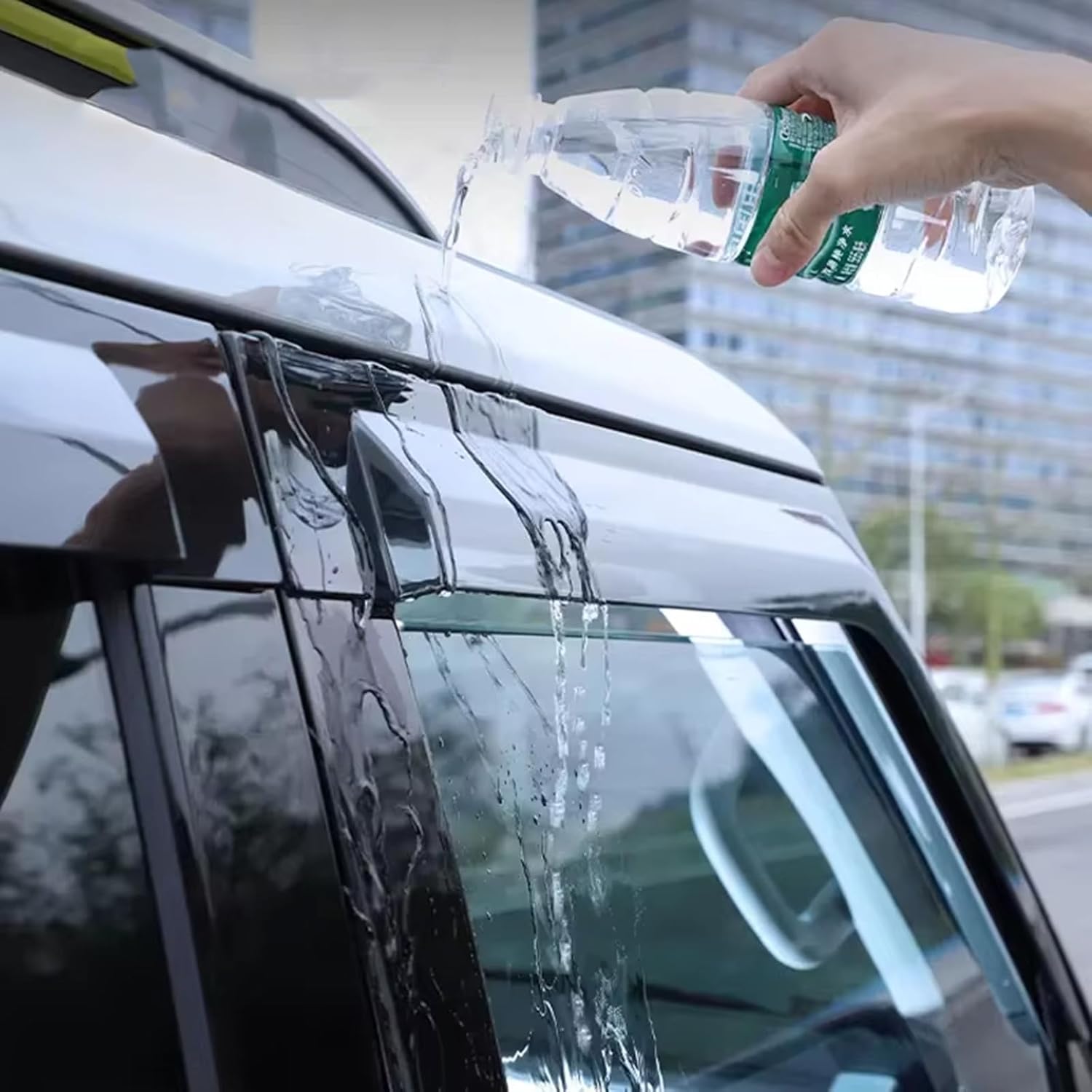 Water being poured over an installed window visor on a car, demonstrating its rain deflection capability
