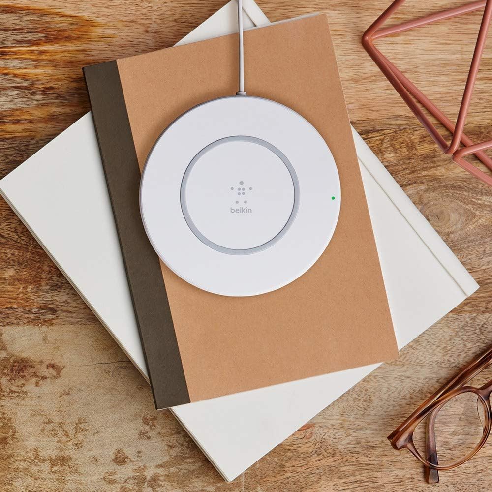 Belkin Quick Wireless Charging Pad on a wooden desk with notebooks